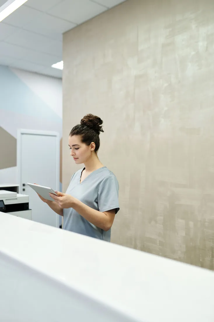 Healthcare worker reviewing a tablet at a clinic reception