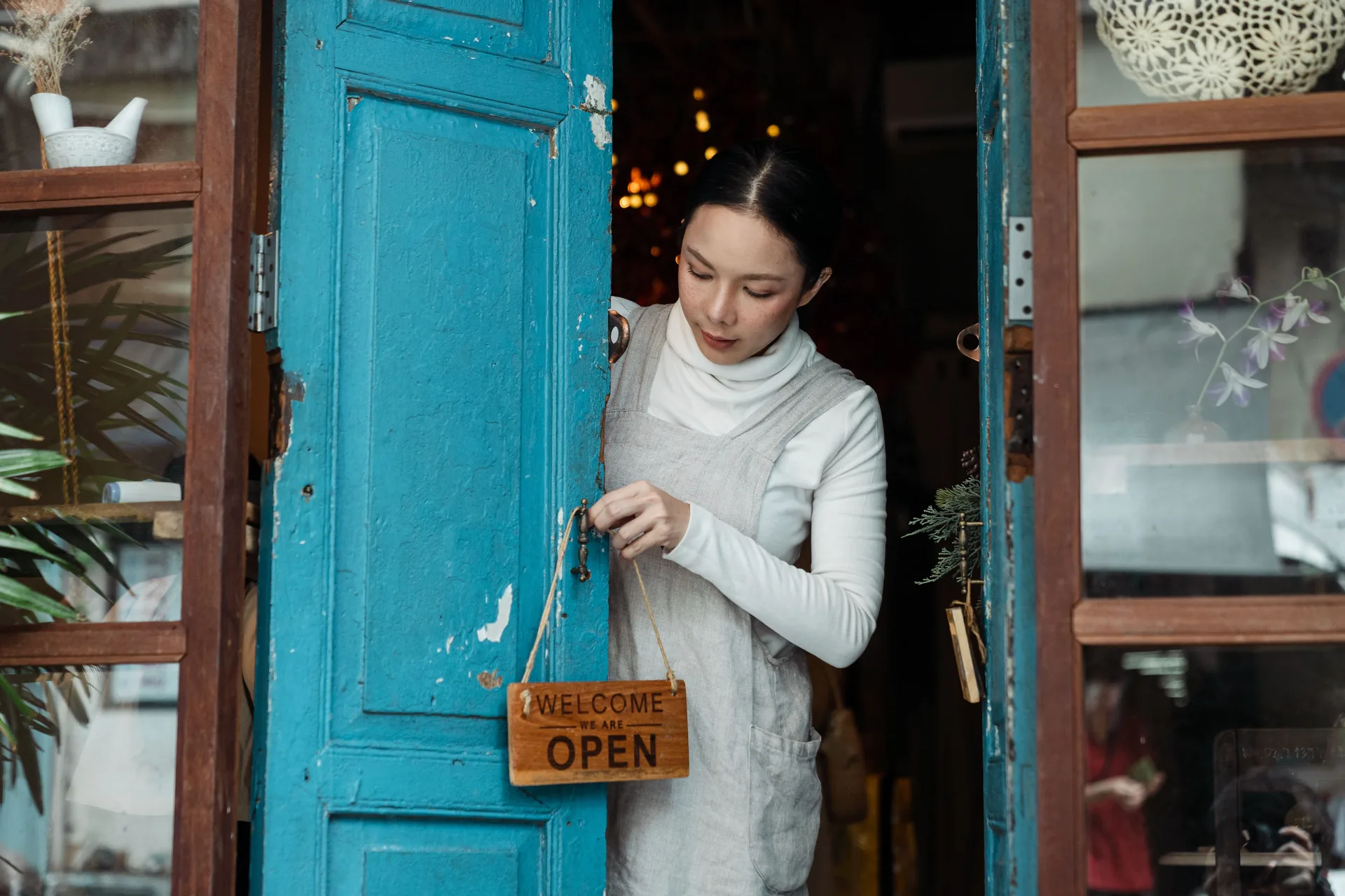Small business owner turning the sign to open at their shop door
