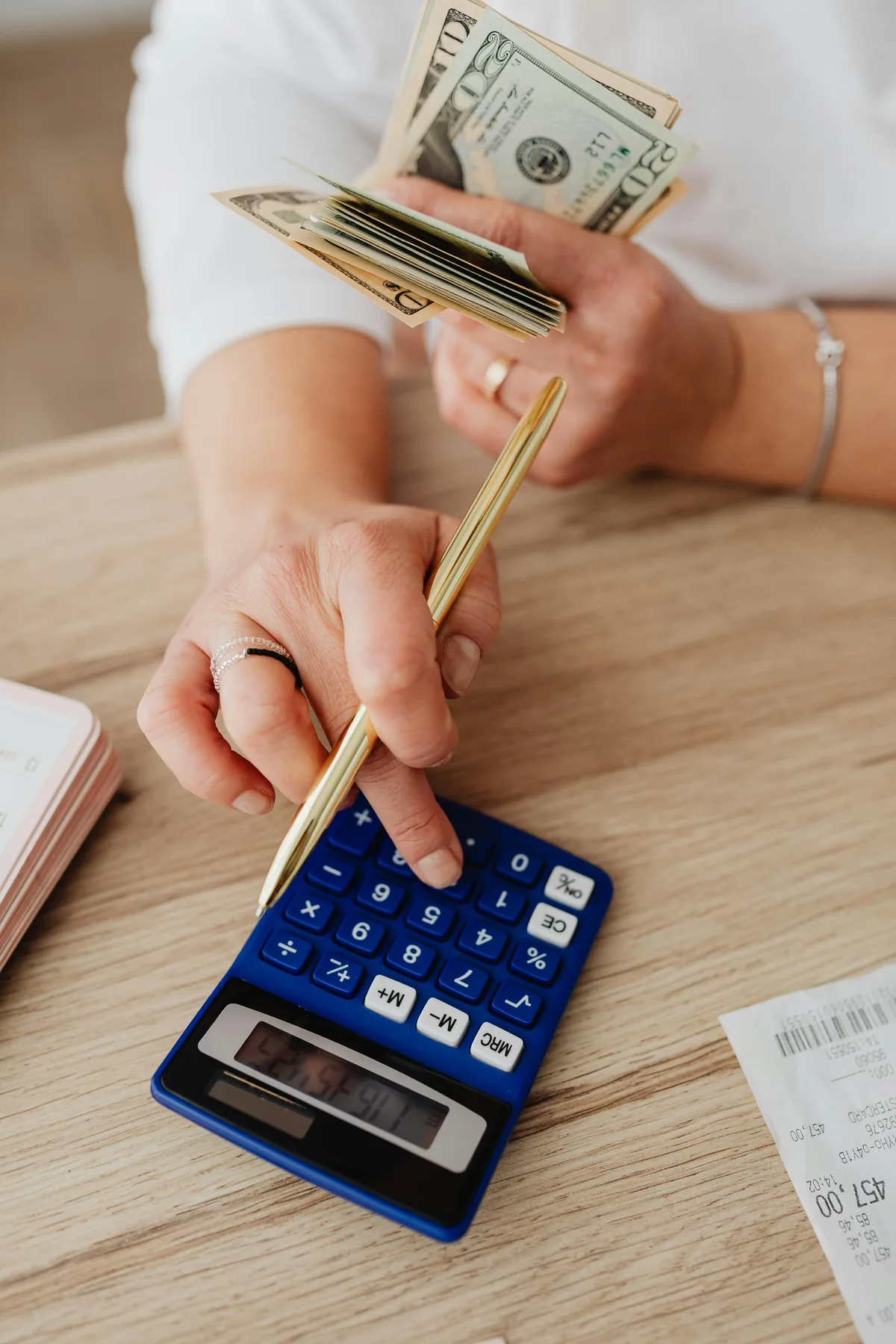 Business owner calculating merchant cash advance debt payments with a calculator and receipts