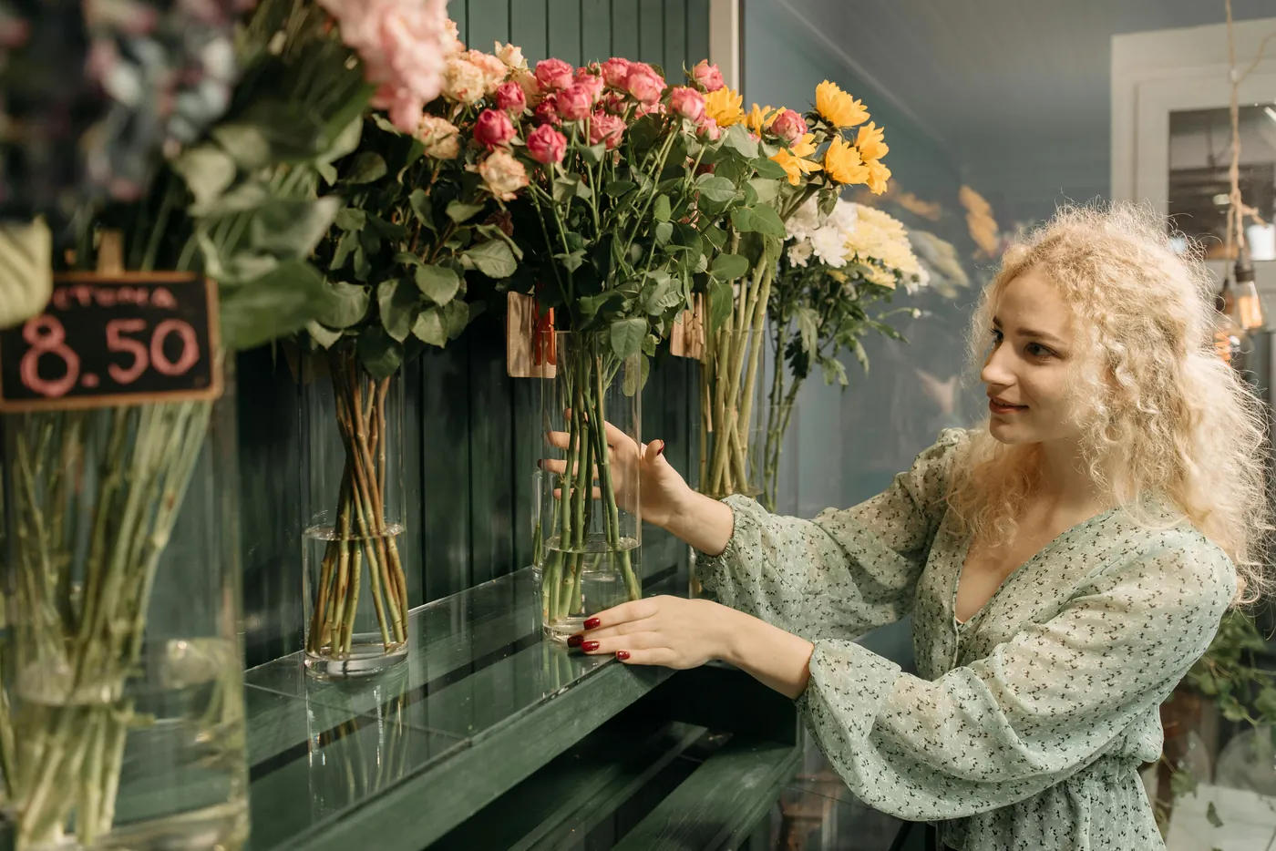 Florist shop owner arranging fresh flowers behind the counter of a small independent retail shop — illustrating the operating environment of a small retail business