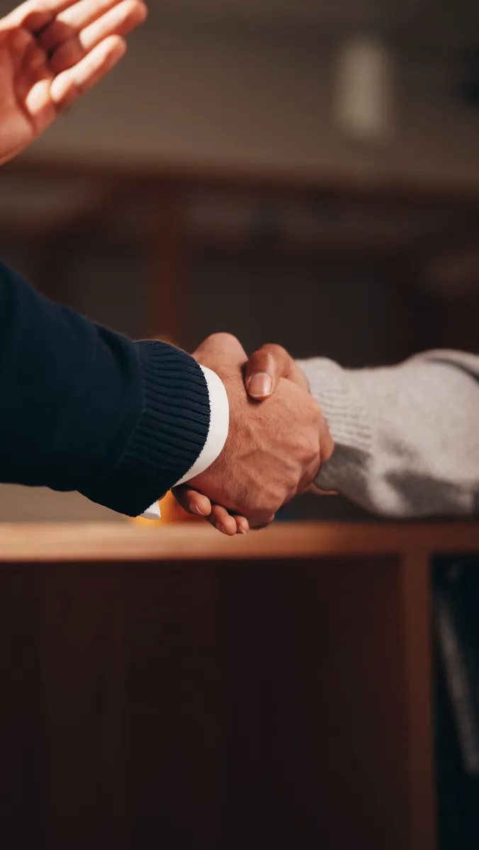 Two people shaking hands across a desk