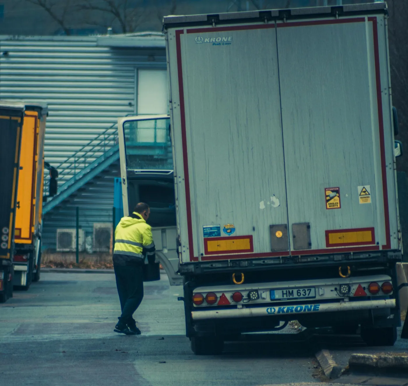 Trucking worker in hi-vis vest unloading freight at a logistics depot — illustrating the small-fleet operating environment